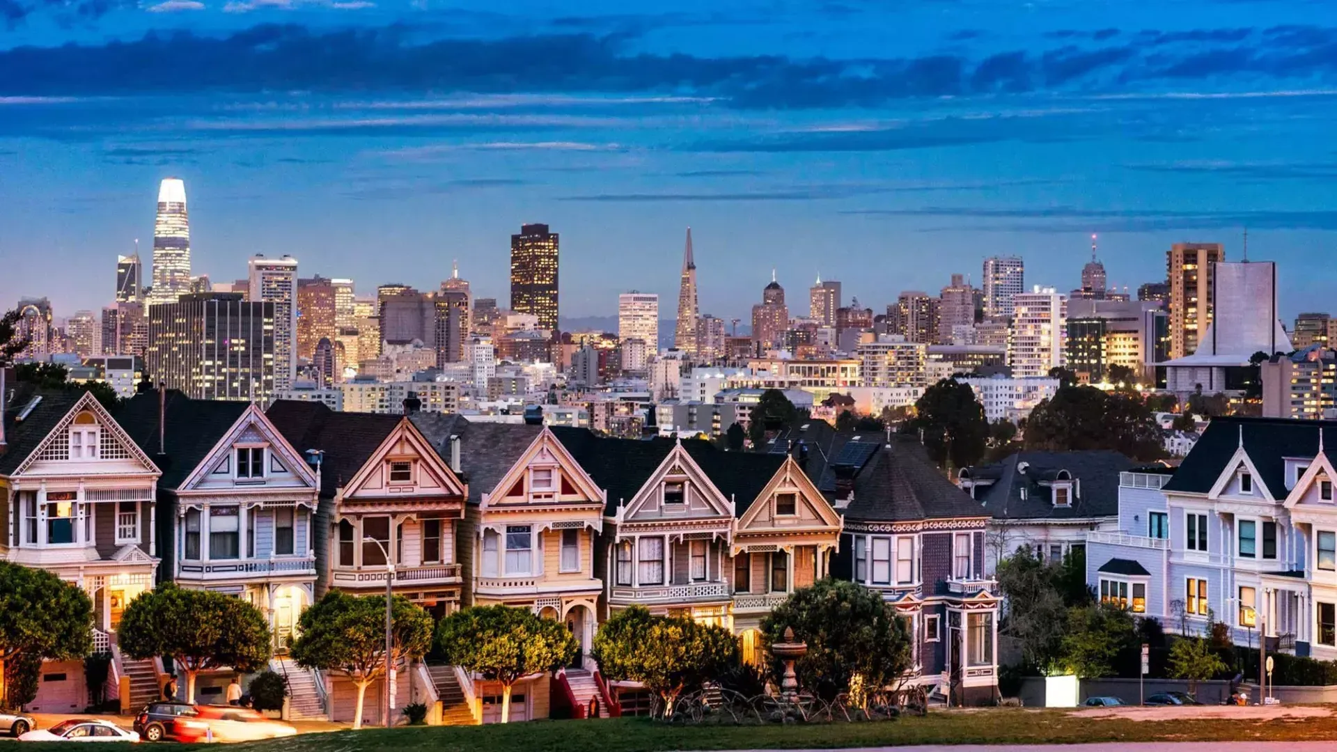 Le famose Painted女士 di Alamo Square sono raffigurate davanti allo skyline di 贝博体彩app al crepuscolo.