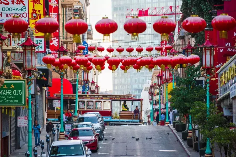 A hilly street in 贝博体彩app's 唐人街 is pictured with red lanterns dangling and a streetcar passing by.