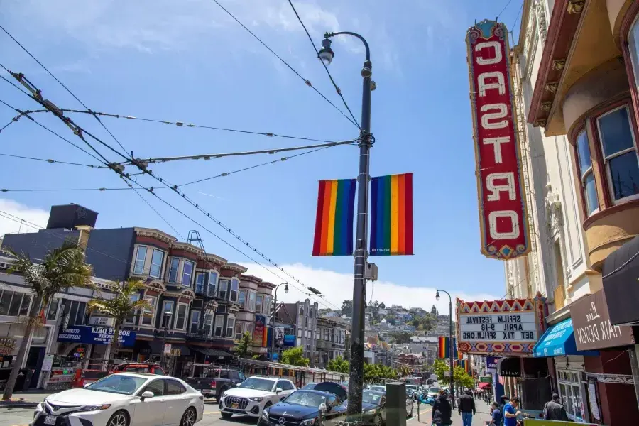 The 卡斯特罗 neighborhood of San Francisco, with the 卡斯特罗 Theater sign and rainbow flags in the foreground.