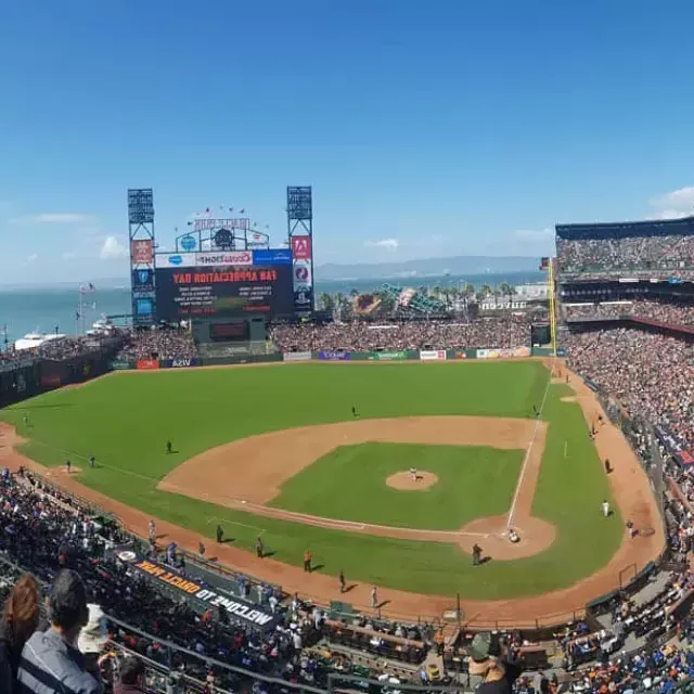 A view of San Francisco's Oracle Park looking out from 的 st和s, 前景是棒球场，背景是贝博体彩app湾.